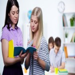 Portrait of teacher looking at her student copybook while explaining mistakes