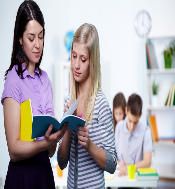 Portrait of teacher looking at her student copybook while explaining mistakes