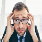 Frustrated businessman in eyeglasses touching his head