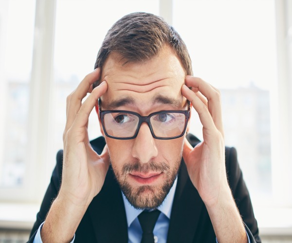 Frustrated businessman in eyeglasses touching his head